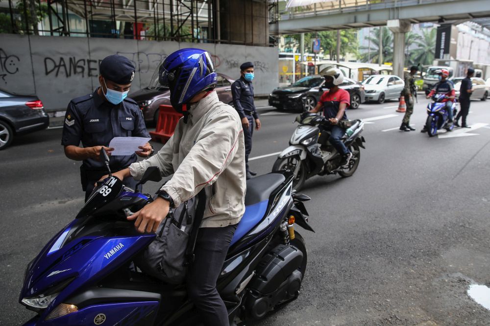 A policeman inspects a motoristu00e2u20acu2122s travel documents during a roadblock on Jalan Syed Putra in Kuala Lumpur October 14, 2020. u00e2u20acu201d Picture by Yusof Mat Isa