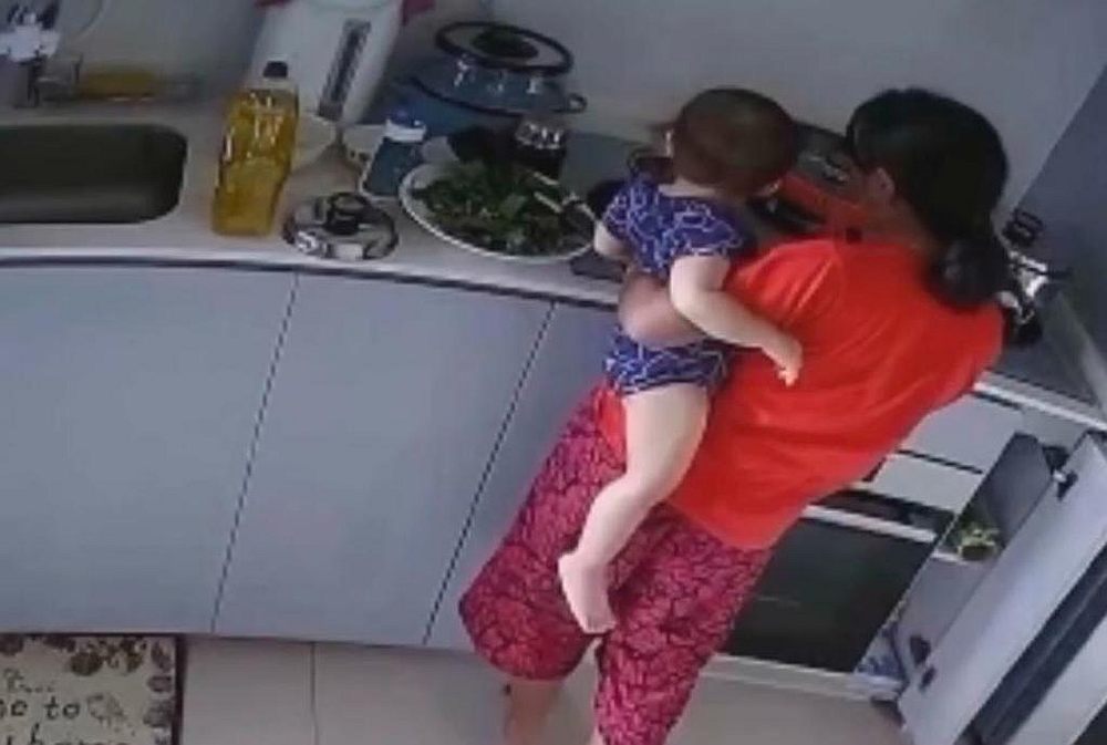 A still photograph taken from CCTV footage of the 30-year-old maid dipping a toddler's hand into a hot pot on a stove. u00e2u20acu201d Picture courtesy of Amy Low Mei Liang/Facebook via TODAY