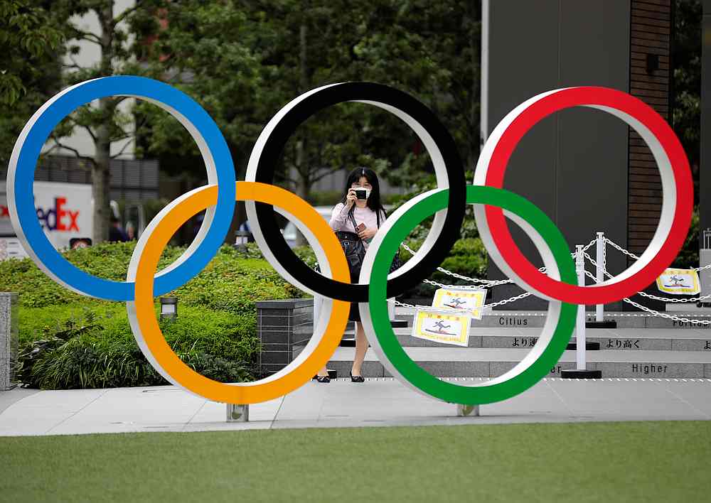 A woman wearing a protective mask amid the Covid-19 outbreak, takes a picture of the Olympic rings in front of the National Stadium in Tokyo, Japan October 14, 2020. u00e2u20acu201d Reuters pic