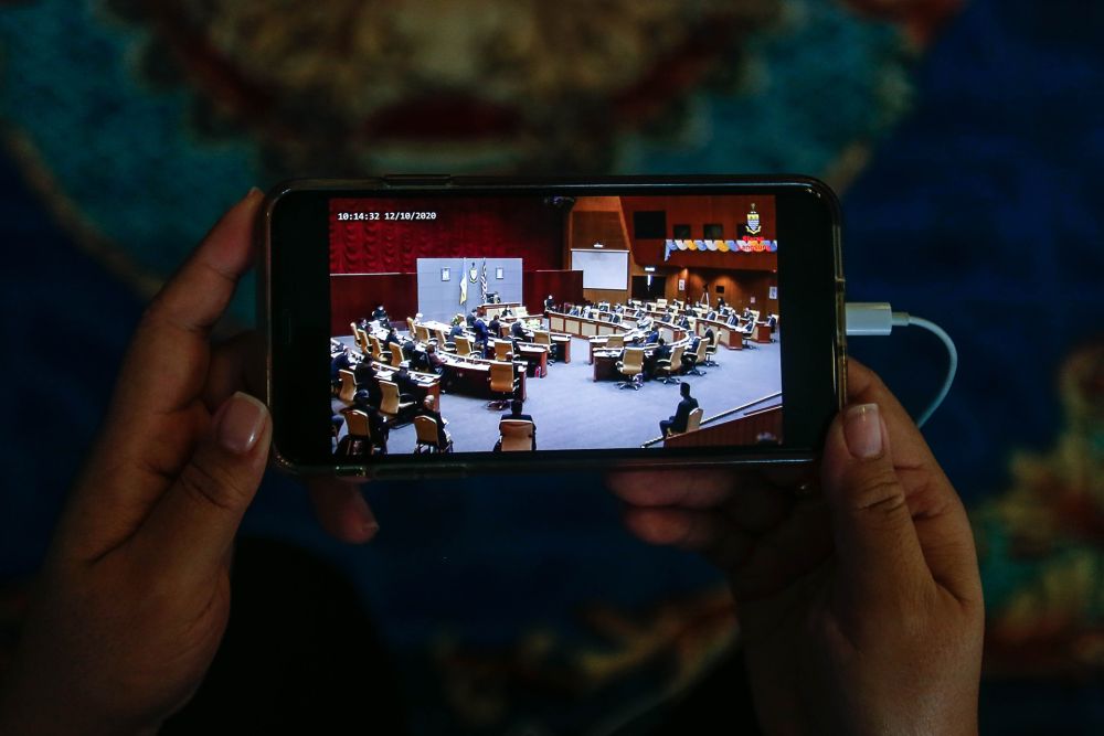 A woman watches a live broadcast of the third term of the 14th Penang State Legislative Assembly session on her phone in George Town October 12, 2020. u00e2u20acu201d Picture by Sayuti Zainudin 