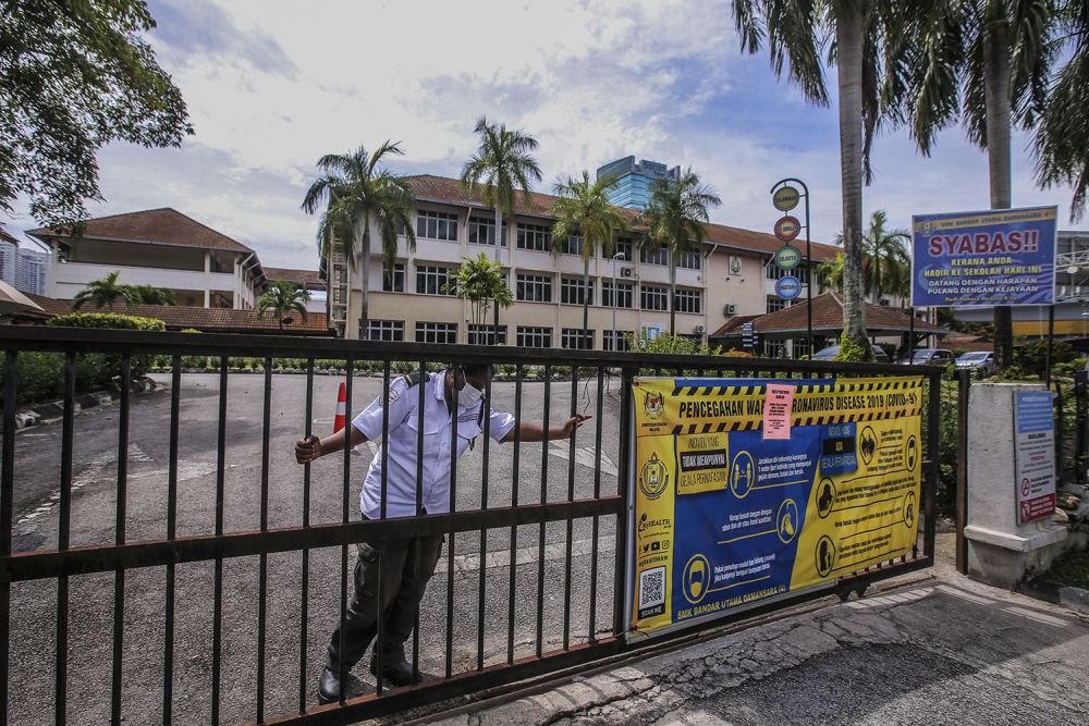 A security guard at Sekolah Menengah Kebangsaan Bandar Utama Damansara 4 closes the school gate in Petaling Jaya October 12, 2020. u00e2u20acu201d Picture by Hari Anggara