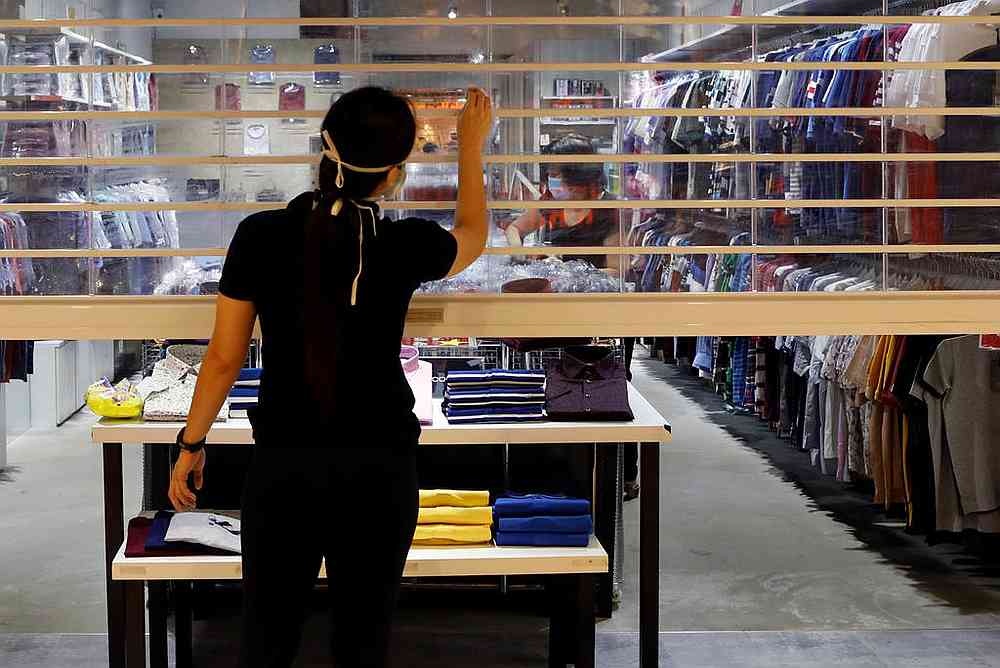 A retail assistant cleaning the shop shutter before opening the Singapore store. MP Jessica Tan urges the government to continue drive for innovation and investing in connected infrastructure.nu00e2u20acu201d Reuters pic 