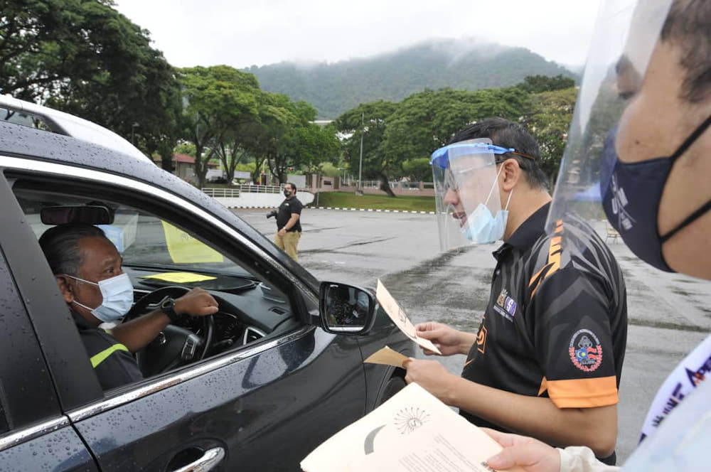 USM Deputy Vice Chancellor (student development affairs and alumni) Professor Aldrin Abdullah explaining the registration process to a parent at the drive-through registration. — Picture courtesy of USM