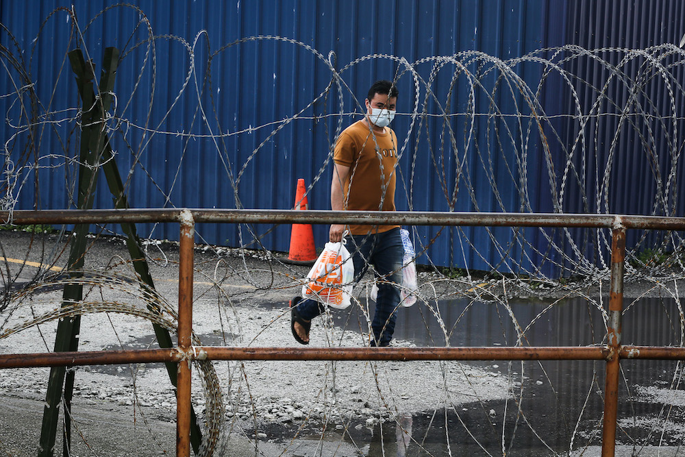 A worker walks past during the enhanced movement control order (EMCO) at Top Glove Corporation Berhad's staff dormitories in Klang November 17, 2020. u00e2u20acu201d Picture by Yusof Mat Isa