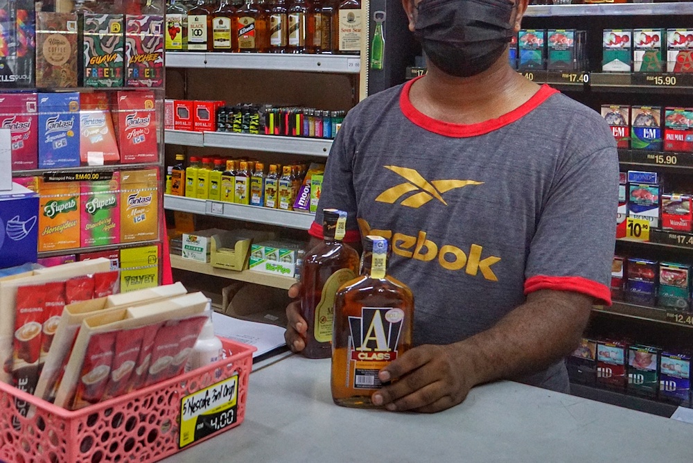 An employee stands in front of liquor bottles in a convenience shop near Sentul November 19, 2020. u00e2u20acu201d Picture by Ahmad Zamzahuri