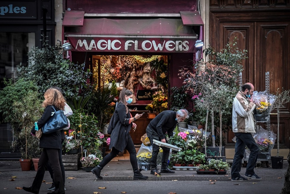 A woman, wearing a face mask, walks in front of a flower shop on October 31, 2020 in Paris on the second day of a second national general lockdown decided by the French government to contain the spread of Covid-19 outbreak. u00e2u20acu201d AFP pic
