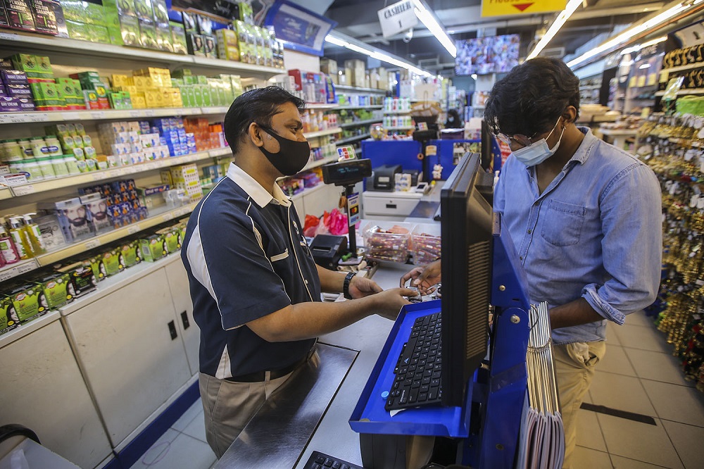 Jahir Hussein (left) attends to customers at his shop in Brickfields, Kuala Lumpur.
