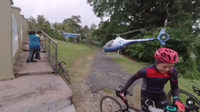A screenshot shows the 9M-HCB helicopter performing a wingover near a group of cyclists. u00e2u20acu201d Picture via Instagram/whynot_lonewolf