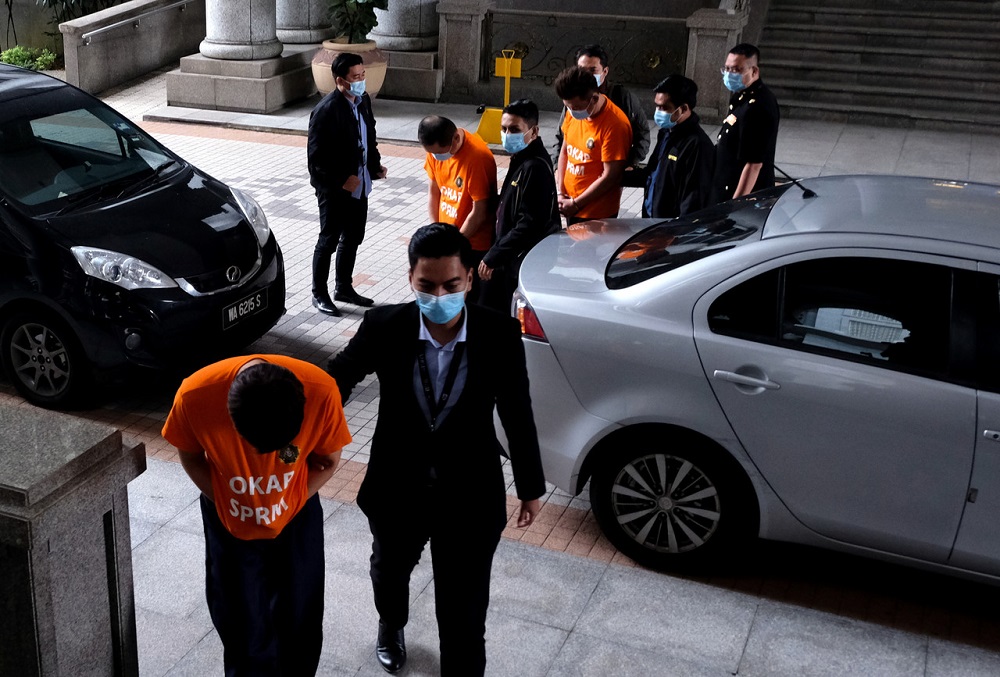 The three suspects, wearing MACC orange lock-up shirts, arrive at the Putrajaya Magistrateu00e2u20acu2122s Court November 10, 2020. u00e2u20acu201d Bernama pic
