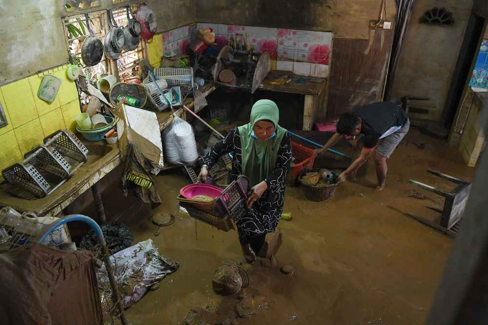 Flood victims Anita Sulong, 50, (left) and her son Muhammad Lokman Hanafi Mohd Ruzilan, 24, move items in their house during the flood in Kampung Teladas, Air Putih November 29, 2020. u00e2u20acu201d Bernama pic