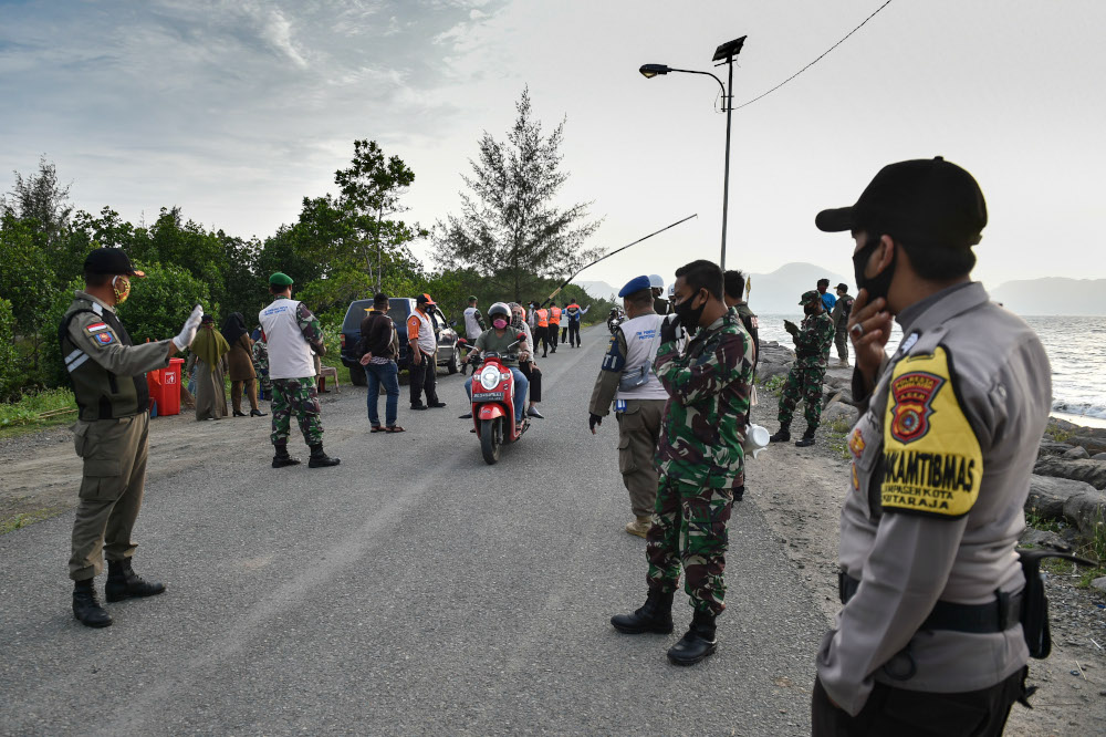 An official (left) stops motorists at a checkpoint as officials enforce government face mask regulations amid the Covid-19 pandemic at a beach in Banda Aceh October 31, 2020. u00e2u20acu201d AFP pic 