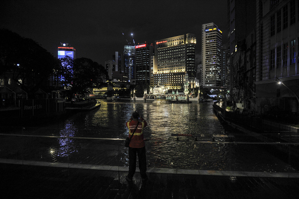 An Alam Flora worker takes a picture of the Klang River near Masjid Jamek which was flooded due to heavy rain November 17, 2020. — Bernama pic