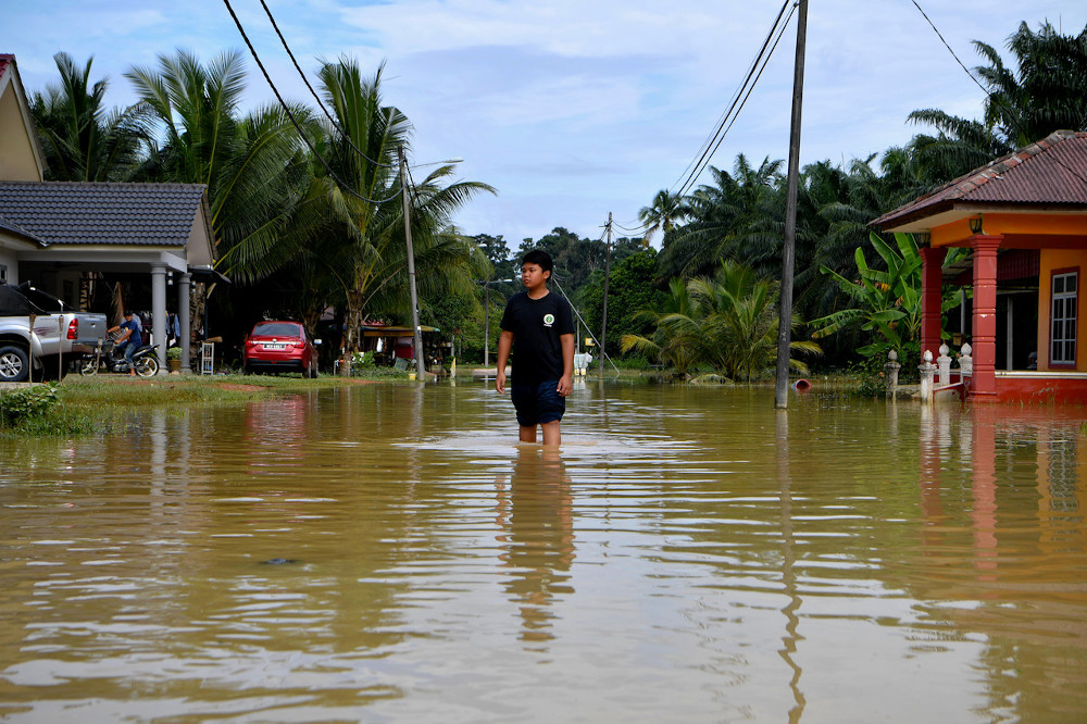 Muhammad Mujahid Mohd Rashid, 11, wades through a flooded road following a flash flood that hit after heavy rain early on Friday morning in Kampung Tehel in Jasin, Melaka, November 23, 2020. u00e2u20acu201d Bernama pic 