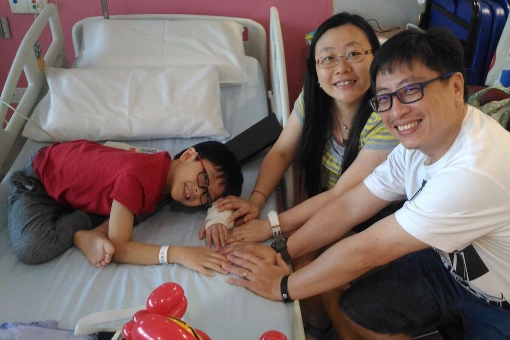 Raphael and his parents, Winnie Lee and William Lee, in the ward before Raphael underwent surgery to amputate his left forearm. — Picture courtesy of Winnie Lee