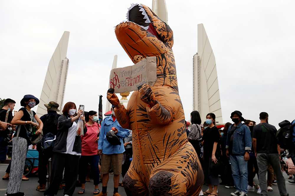 A demonstrator wearing a T-Rex costume carries a sign during a rally to call for the ouster of Prime Minister Prayuth Chan-ocha's government and reforms in the monarchy in Bangkok, Thailand November 8, 2020. u00e2u20acu201d Reuters pic