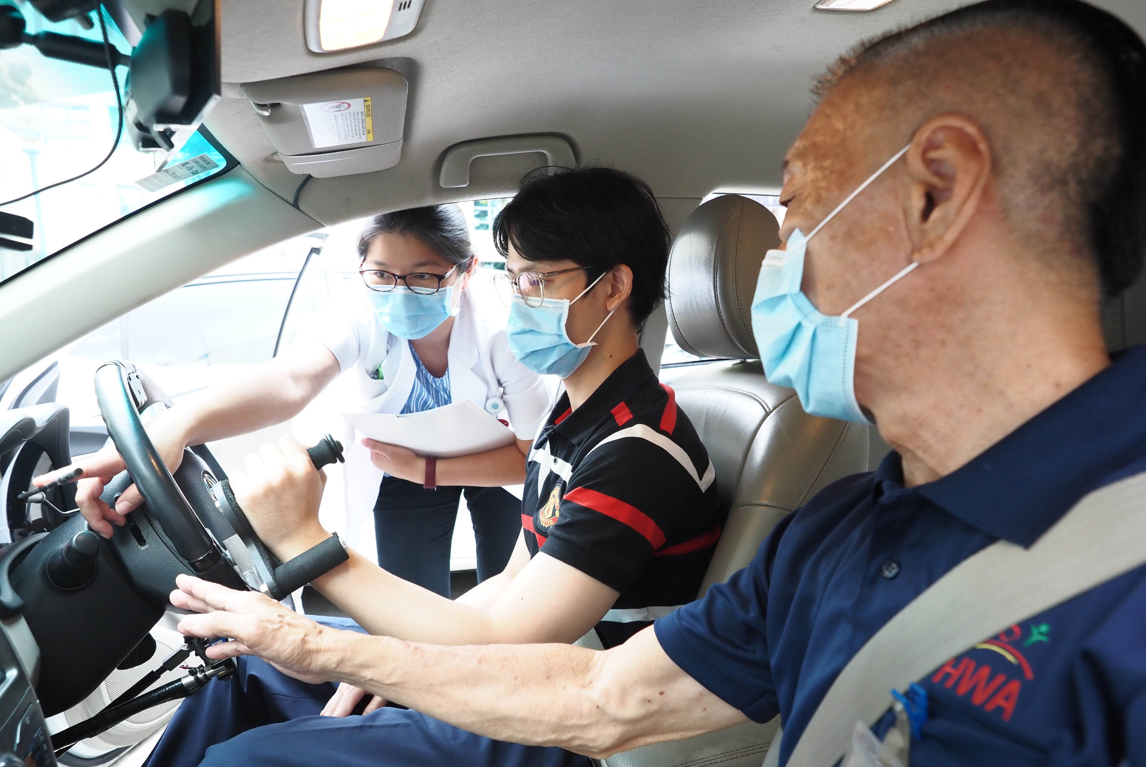 A man undergoing an on-road assessment in a modified vehicle with senior occupational therapist Lim Hui Hui (left) of Tan Tock Seng Hospital and a driving instructor (right) from the Handicaps Welfare Association. — Tan Tock Seng Hospital pic