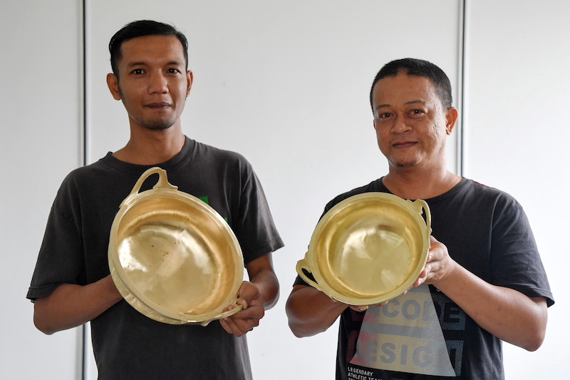 Shaiful Sani Zakaria and Azuan Aziz hold up two brass pots produced by their company SA Unique Craft. u00e2u20acu201d Bernama pic