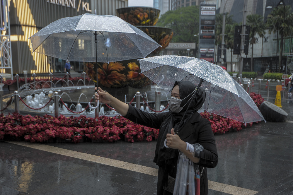 An umbrella vendor holding umbrellas during the rain in Bukit Bintang, Kuala Lumpur December 10, 2020. u00e2u20acu201d Picture by Shafwan Zaidon