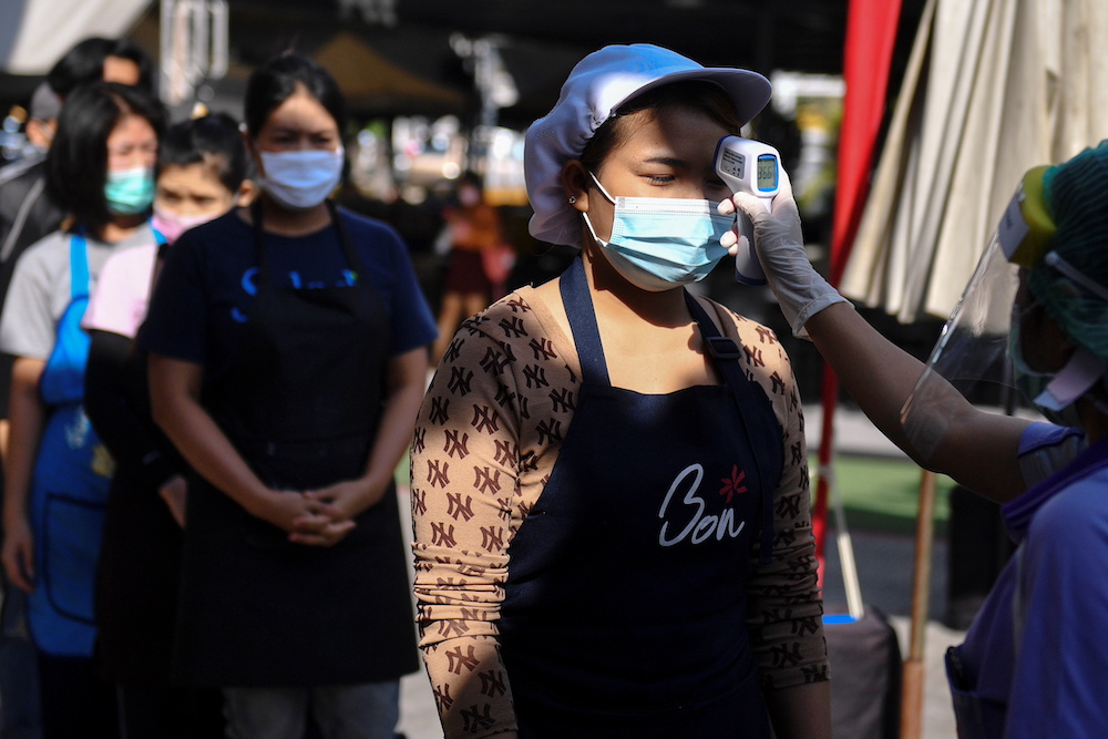 A migrant worker has her temperature checked as she queues to talk with the public health authorities for a Covid-19 investigation at a fresh market in Bangkok, Thailand December 22, 2020. u00e2u20acu201d Reuters pic