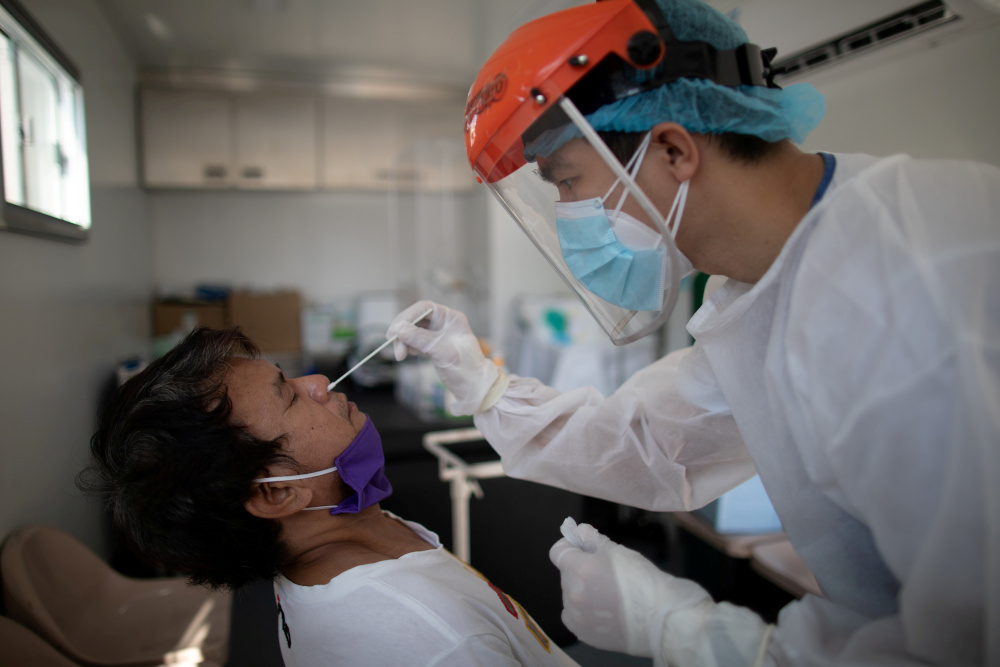 A nurse gets a swab from a man under observation for coronavirus disease in a booth set up in a hospital parking lot in Manila, Philippines, April 15, 2020. u00e2u20acu201d Reuters picnn