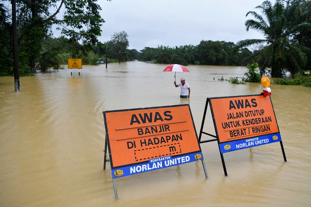 A man wades in flood water as he crosses a road at Kampung Tebak in Air Putih, Kemaman December 18, 2020. u00e2u20acu201d Bernama pic