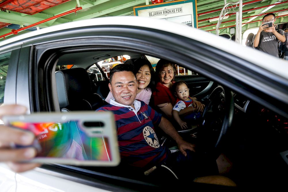 Soon Yong Khion, 40, along with his family taking a selfie while boarding the ferry service for the last time here at Pengkalan Raja Tun Uda Ferry Terminal, December 31, 2020. — Picture by Sayuti Zainudin