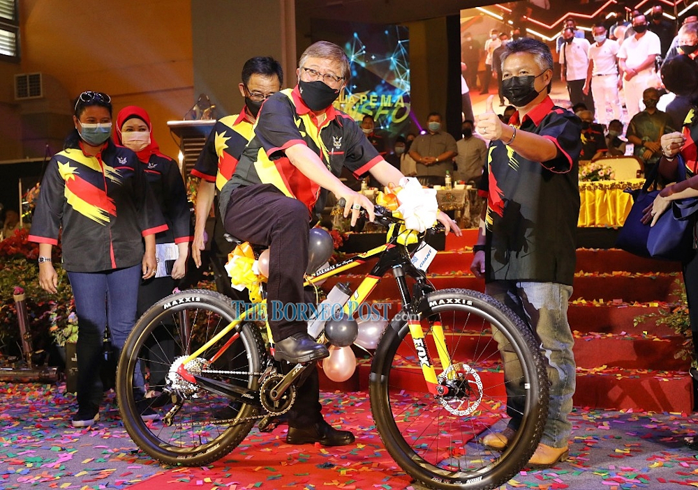 Datuk Patinggi Abang Johari Openg rides a bicycle presented to him as a token of appreciation as Assistant Youth and Sports Minister Datuk Snowdan Lawan (right) flashes a thumbs-up. u00e2u20acu201d Picture by Chimon Upon/Borneo Post