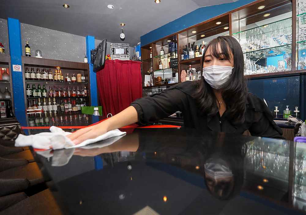 Mabel, who owns Bell Bar at Cuppage Plaza, disinfecting a countertop. u00e2u20acu201d TODAY pic