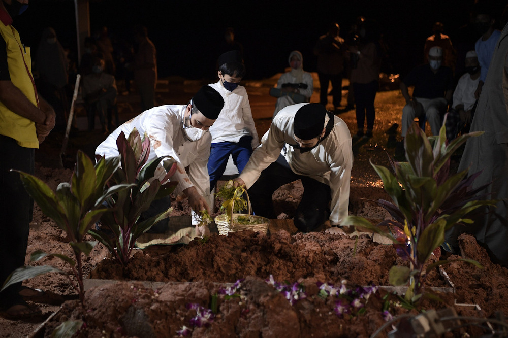 Family members scatter flowers at the grave of the late Royal Prof Ungku Abdul Aziz Abdul Hamid at the Bukit Kiara Muslim Cemetery December 15, 2020. u00e2u20acu201d Bernama pic