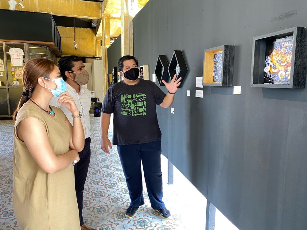 One of the artists, Nasir Nadzir (right) who painted blueberries inside one box and French toasts topped with blueberries and bananas in another box explaining the rationale behind his artwork to Ivan and gallery manager Wanida Razali.