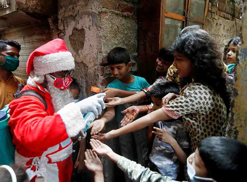 A man wearing a Santa Claus costume sanitises children's hands inside a slum, amid the spread of Covid-19, in Mumbai, India December 19, 2020. u00e2u20acu201d Reuters pic