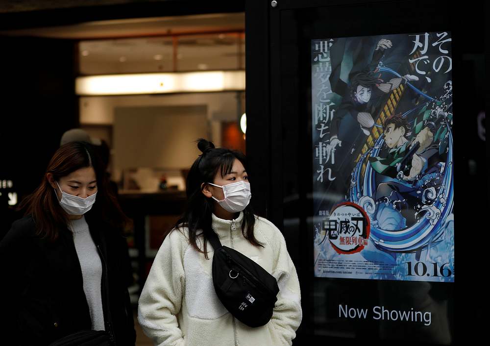 Women wearing protective masks amid the Covid-19 outbreak walk past a poster for an animated movie 'Demon Slayer' in front of a movie theatre in Tokyo, Japan December 13, 2020. u00e2u20acu201d Reuters pic