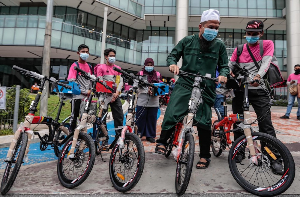 Ustaz Ebit Lew (in green) presenting the lightweight bicycles to help the delivery walkers with their food orders around Kuala Lumpur. u00e2u20acu201d Picture via Facebook/EbitLew  