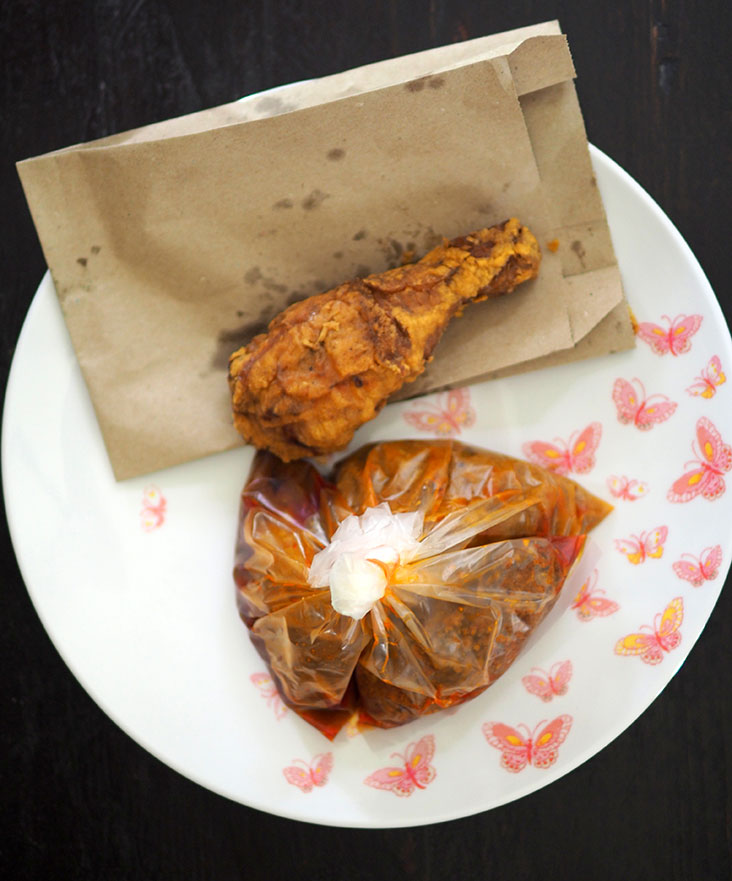 The side dishes are placed in separate packets while the fried chicken is placed in a brown paper bag