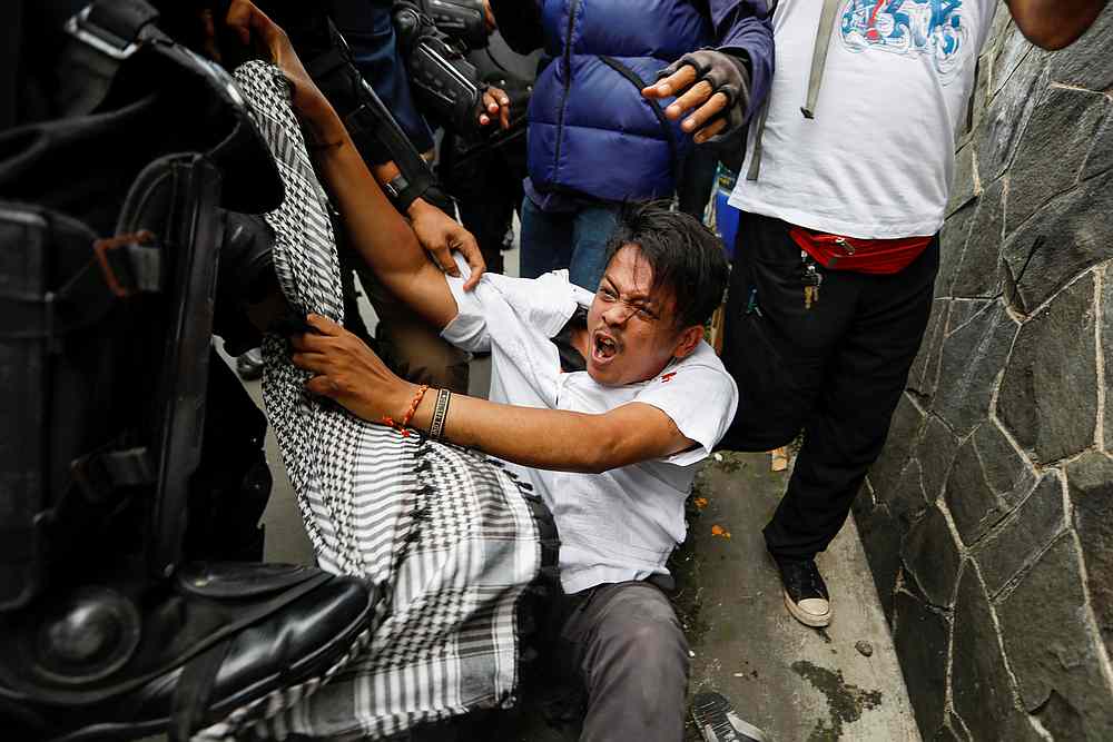 A man reacts while being detained by riot police officers during a protest over the detention of Rizieq Shihab, the leader of Indonesian Islamic Defenders Front (FPI), in Jakarta, Indonesia, December 18, 2020.  u00e2u20acu201d Reuters picn