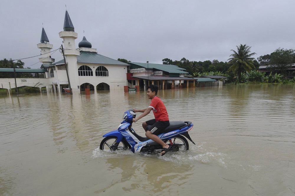 A motorcyclist rides through flood waters in Kampung Chenulang, Kuala Krai December 18, 2020. u00e2u20acu2022 Bernama pic