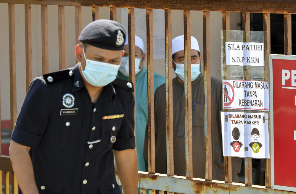 A police officer guards the entrance that houses the occupants of Madrasah Daril Naim, Melor, Kelantan, December 28, 2020.  u00e2u20acu201d Bernama pic 