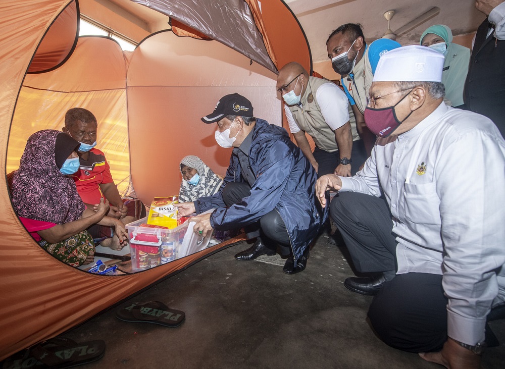 Prime Minister Tan Sri Muhyiddin Yassin spent some time mingling with flood victims comprising 154 people from 59 families housed at the relief centre and presented aid in the form of food supply to them, December 22, 2020. u00e2u20acu2022 Bernama pic