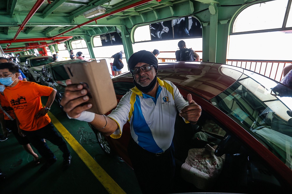 Menjit Singh, 59, takes a selfie onboard the ferry service for the last time at the Pengkalan Raja Tun Uda Terminal  December 31, 2020.  ― Picture  by Sayuti Zainudin