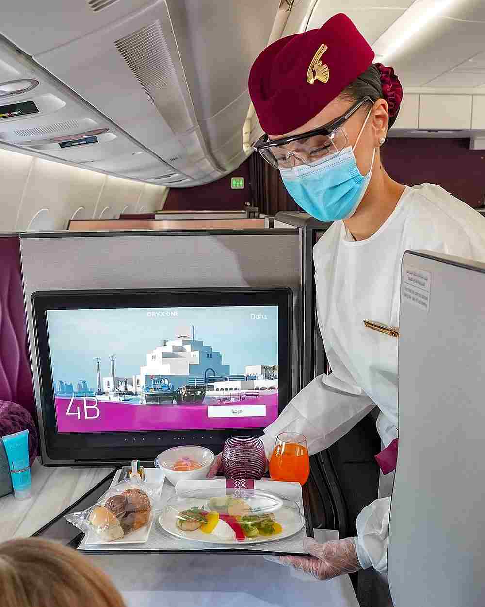 A Qatar Airways flight crew serves a meal to a passenger. — Picture from Instagram/Qatar Airways