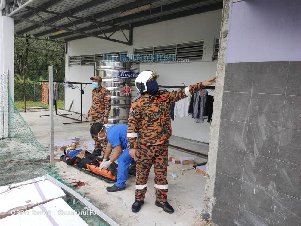 The victim is placed in a stretcher by paramedics as a rescue worker examines whatu00e2u20acu2122s left of the wall. u00e2u20acu201d Picture by Borneo Post