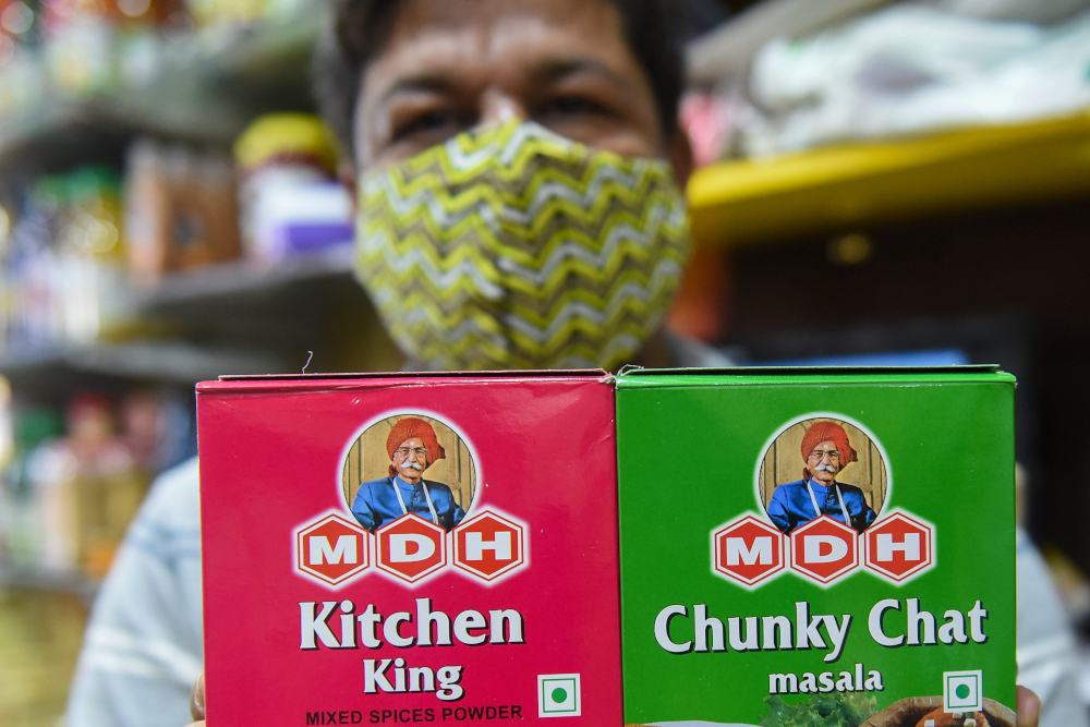 A man poses holding packets MDH Spices featuring a picture of founder Dharampal Gulati at a store in Ahmedabad on December 4, 2020. u00e2u20acu201d AFP picnn