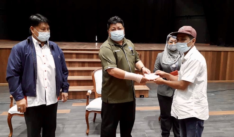 Johor Education, Information, Heritage and Culture Committee chairman Mazlan Bujang (centre) presents a contribution during the Covid-19 Assistance Delivery Programme to Entrepreneurs and Taxi Drivers in Johor Baru. u00e2u20acu201d Picture by Ben Tan