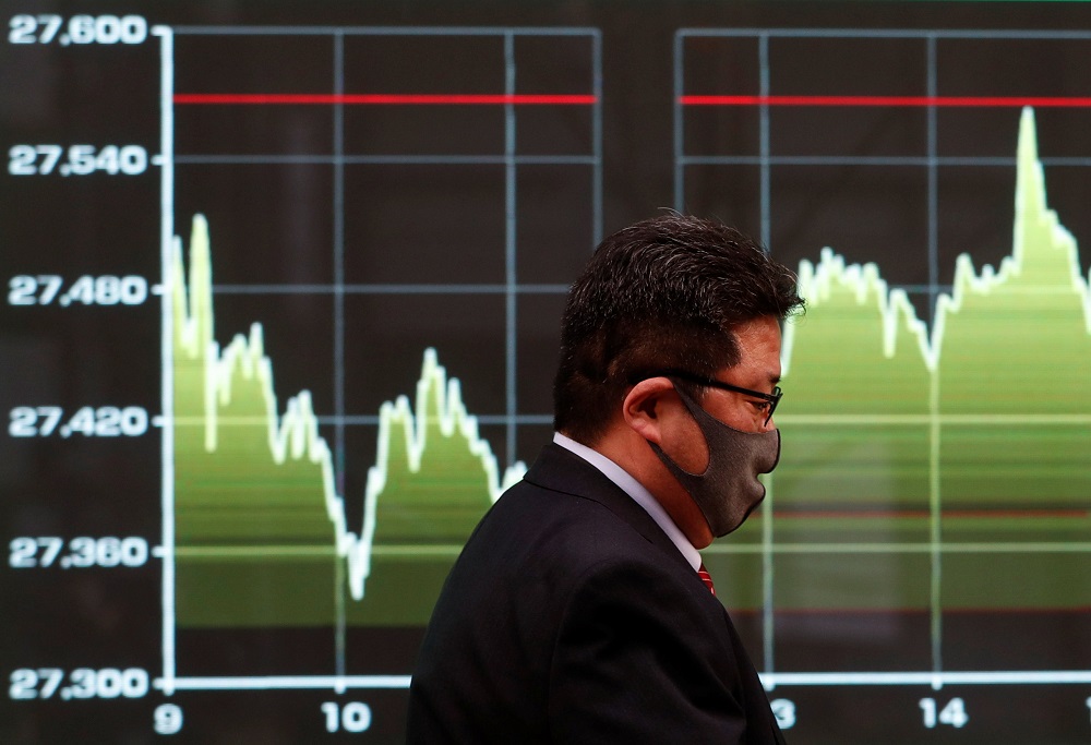 A man wearing a protective face mask walks past a screen displaying a graph showing recent Nikkei share average movements outside a brokerage in Tokyo December 30, 2020. u00e2u20acu201d Reuters pic