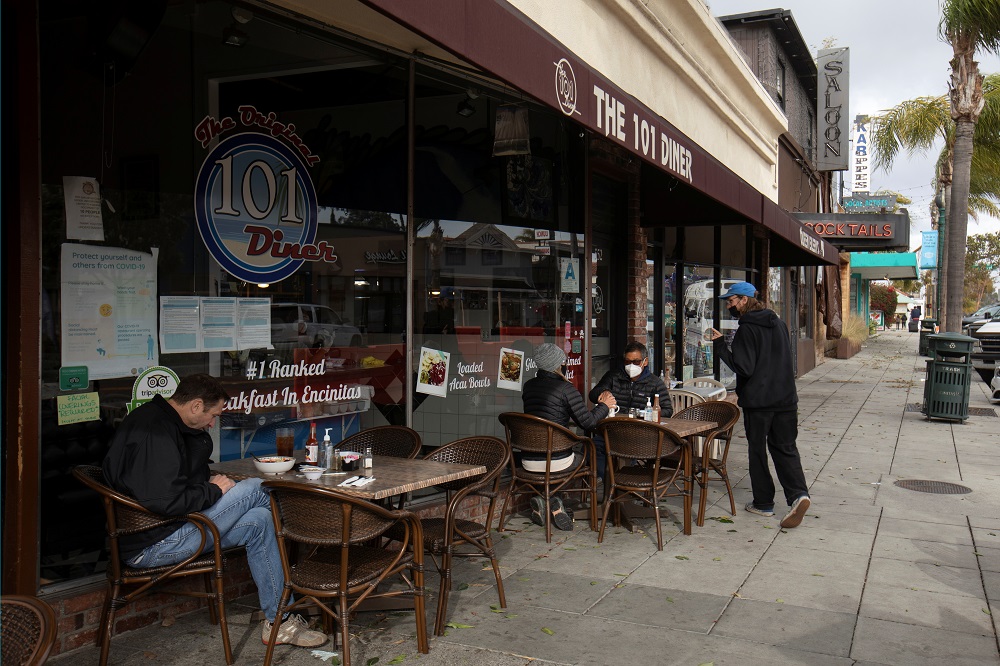 People sit outside along a sidewalk at a diner after California lifted its regional stay-at-home orders across the state during the outbreak of the coronavirus disease, in Encinitas, California January 25, 2021. u00e2u20acu201d Reuters pic
