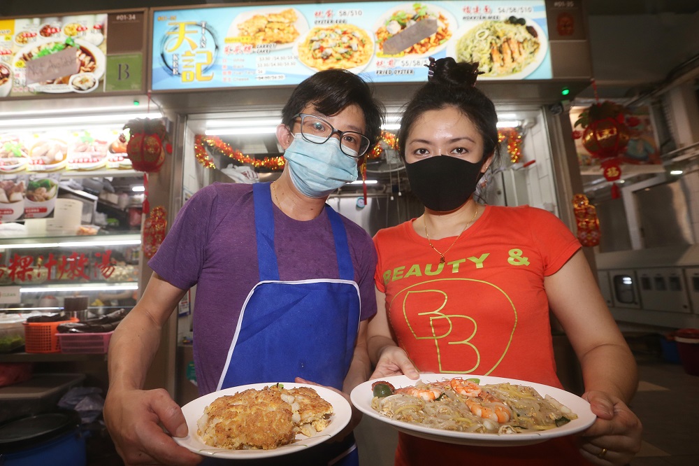 Elayne Ang, holding a plate of Hokkien mee, and Samuel Tan, with a plate of fried carrot cake, at their stall Tien Kee Carrot Cake/Hokkien Mee located at Blk 84, Marine Parade Central. — TODAY pic