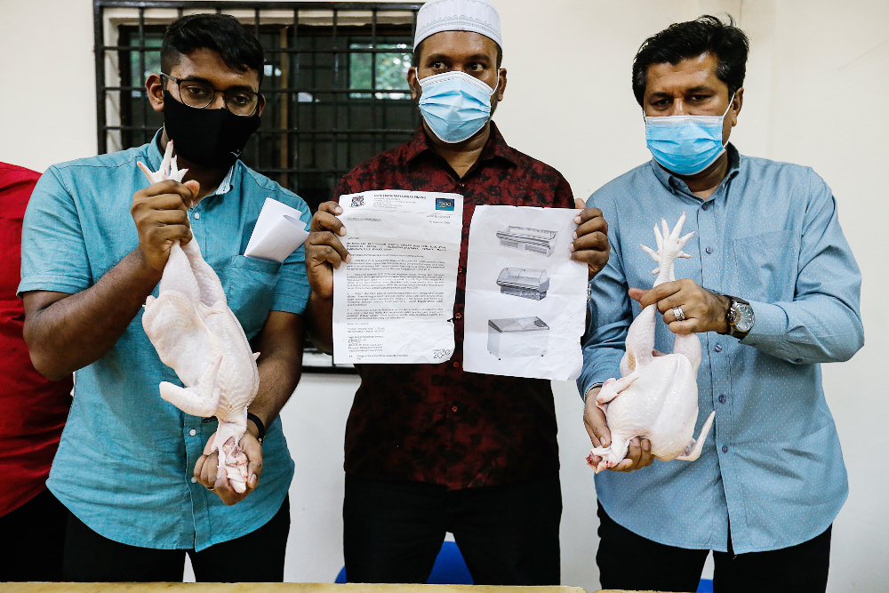 Penang Traders Association Chairman Azizurahman A. Dzulkarnain (centre) and association members show the difference between slaughtered (left) and frozen (right) chicken in Penang January 11, 2021. u00e2u20acu201d Picture by Sayuti Zainudin