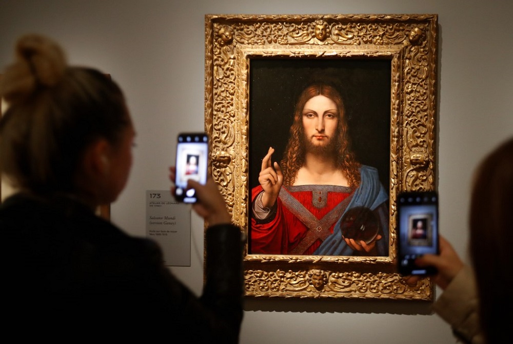 In this file photograph taken on October 22, 2019, visitors take photographs with mobile phone of the oil painting by Leonardo da Vinci u00e2u20acu02dcSalvator Mundiu00e2u20acu2122 at The Louvre Museum in Paris. u00e2u20acu201d AFP pic
