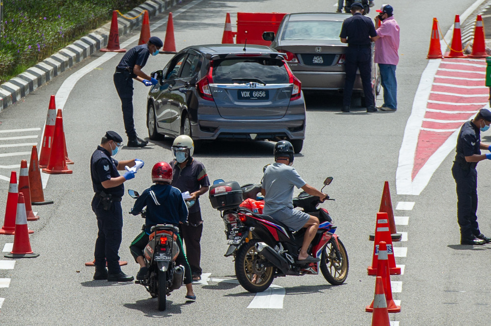 Police officers conducting checks at a roadblock in Jalan Kuching, Kuala Lumpur January 31, 2021. u00e2u20acu201d Picture by Shafwan Zaidon 