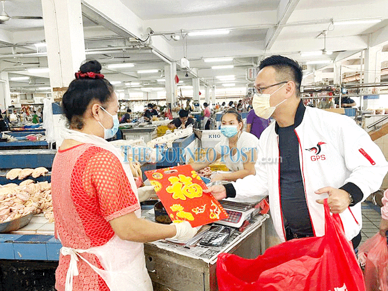 Foo (right) hands out the couplet to a hawker at Kenyalang Market. u00e2u20acu201d Borneo Post Online pic